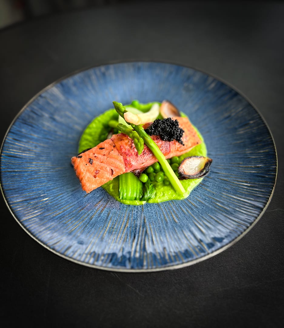 Filetto di salmone su crema di piselli e asparagi, servito con caviale vegano e cipolla caramellata